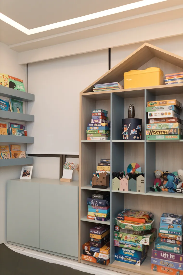 Sala para crianças e adolescentes, com estante em formato de casa cheia de jogos e livros
